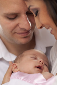 Happy Young Attractive Mixed Race Couple with Newborn Baby.