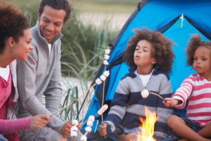 Family Camping On Beach And Toasting Marshmallows