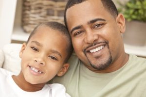 A happy African American man and boy, father and son, family sitting together at home