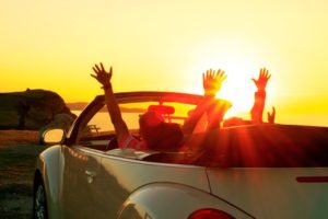 Happy family  in a cabriolet convertible car at the sunset in summer