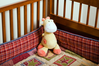 Yellow stuffed animal giraffe in empty baby crib