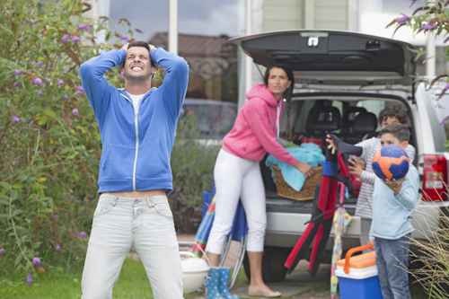 Frustrated father shouting as family packs car for vacation