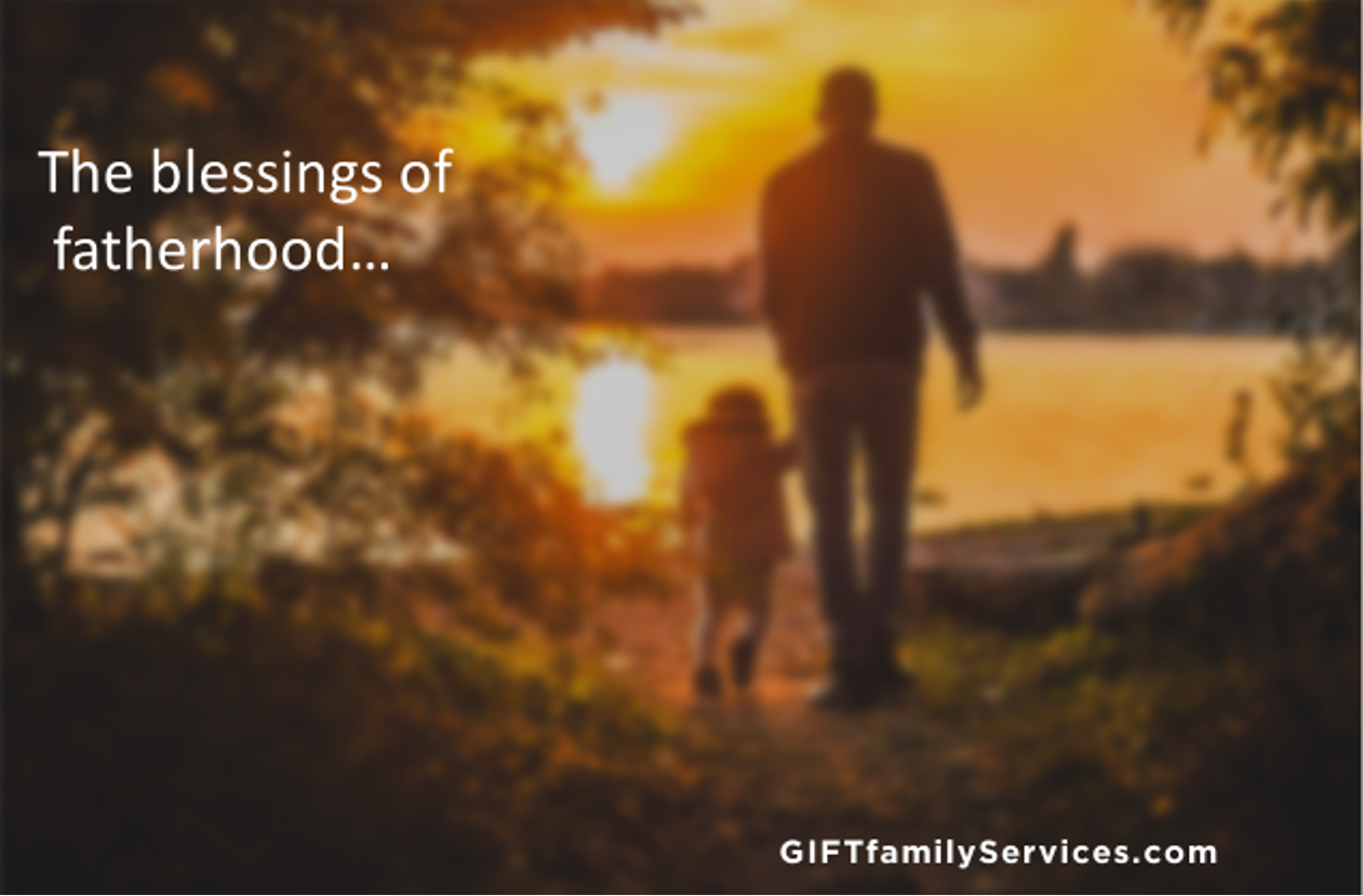A silhouette of a father and child walking by the lake at sunset.