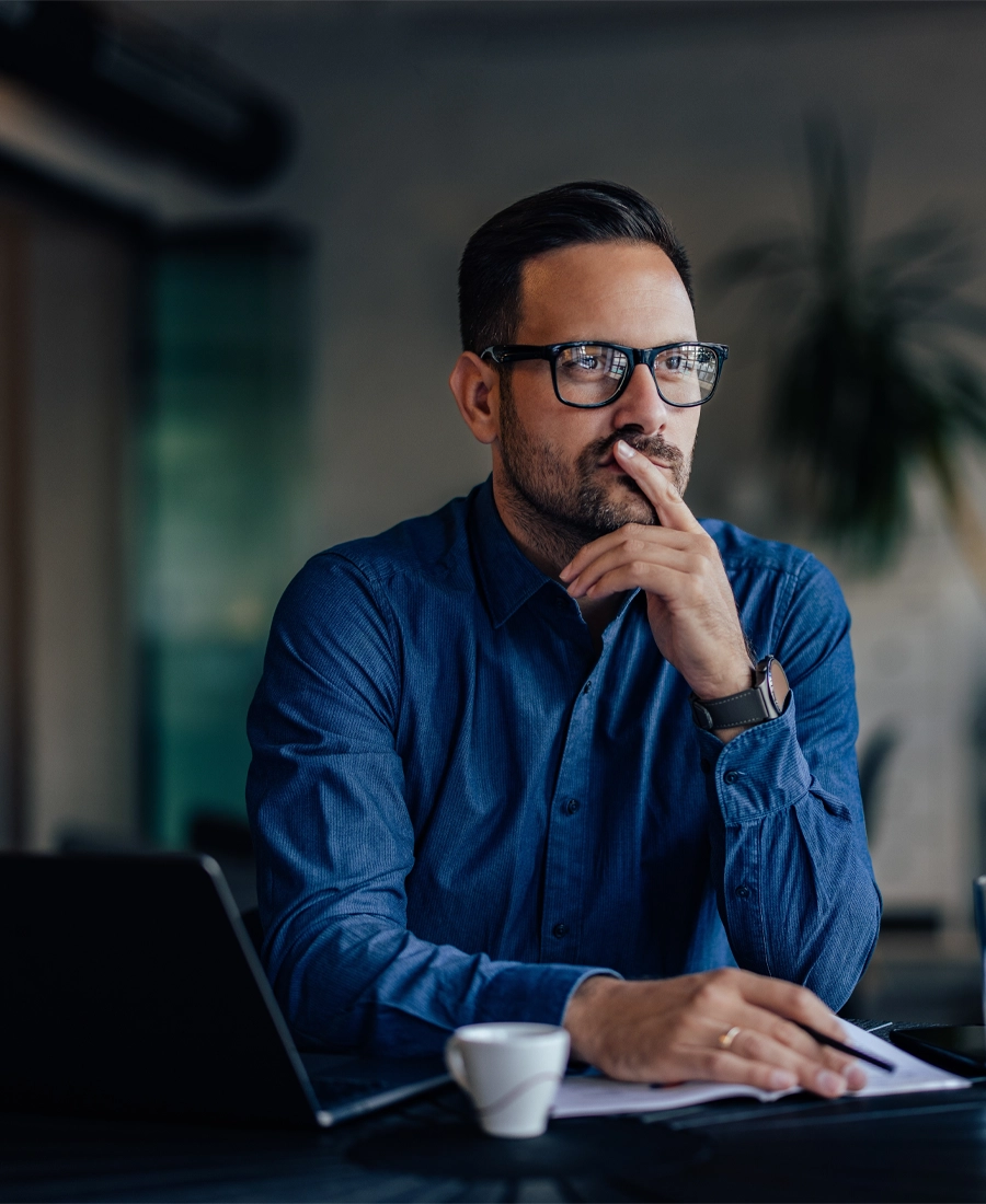 Adopt Main image Man in glasses sitting at a desk, thinking