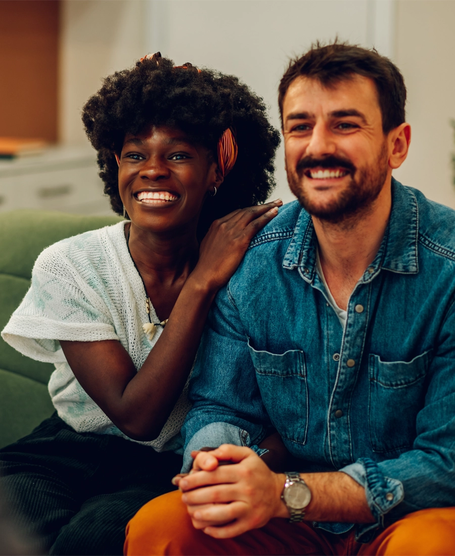 Smiling couple sitting close together on a sofa at home