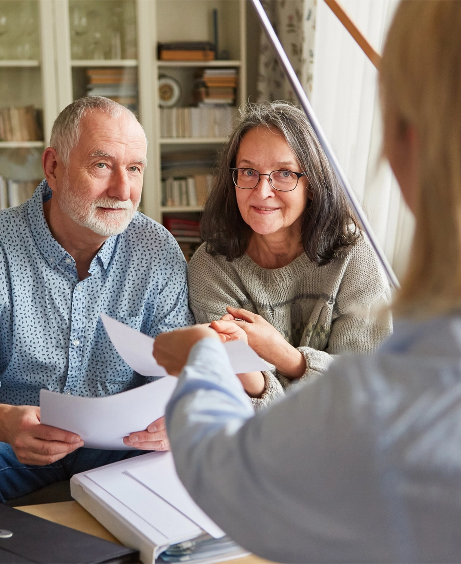 Older couple smiling as they go through paperwork with a coach
