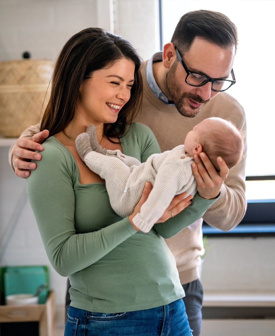 Smiling parents holding their baby at home