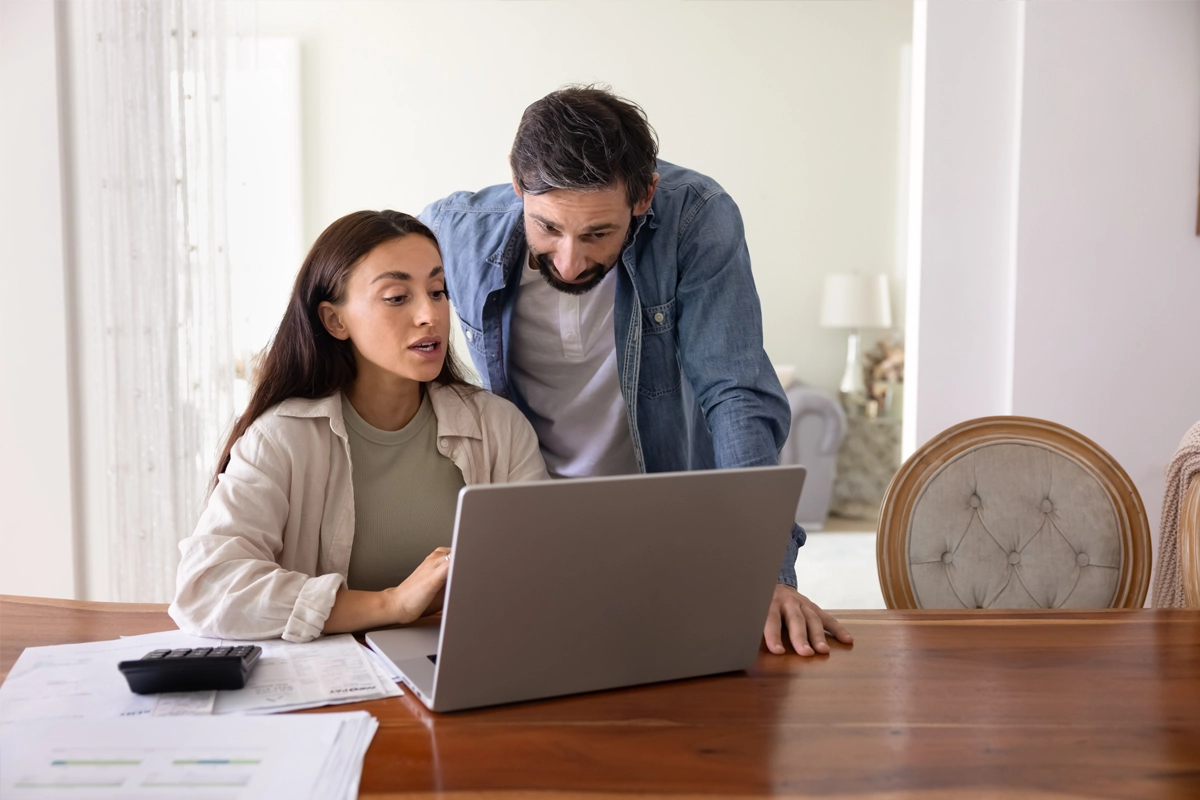 Couple looking at a laptop together at a table at home