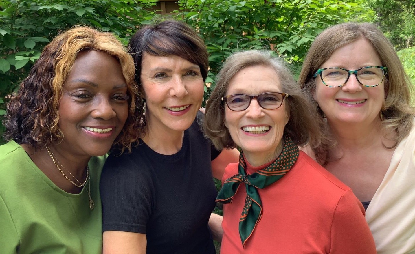 Four GIFT coaches smiling together outdoors